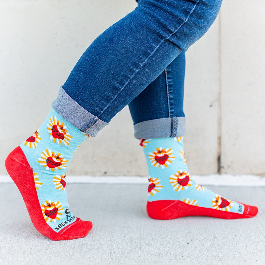 a woman's feet wearing a pair of red and blue Sacred Heart socks