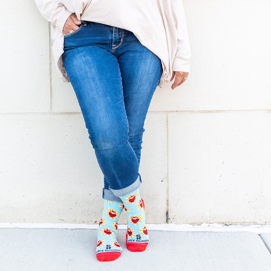 a woman wearing blue jeans and a pair of red and blue Sacred Heart socks