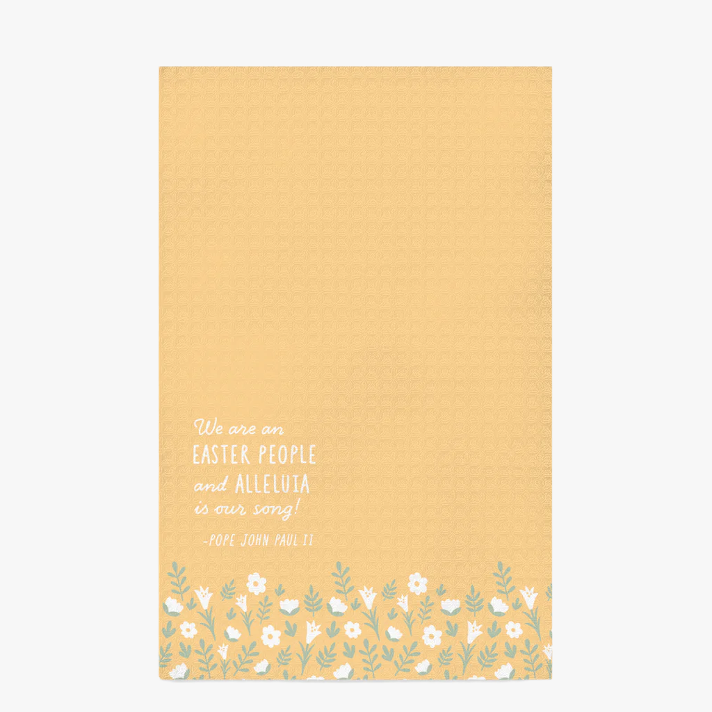 Yellow, waffle textured dish towel, laid flat on a white background, showing the design of subtle white flowers and pale green leaves with the wordings that say "We are an EASTER PEOPLE and ALLELUIA is our song! -Pope John Paul II" 