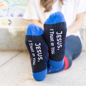 a woman wearing Divine Mercy dress socks showing bottom of foot that reads "Jesus, I trust in you"