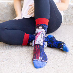 a woman sitting with legs crossed wearing a pair of catholic dress socks featuring the Divine Mercy Image of Jesus