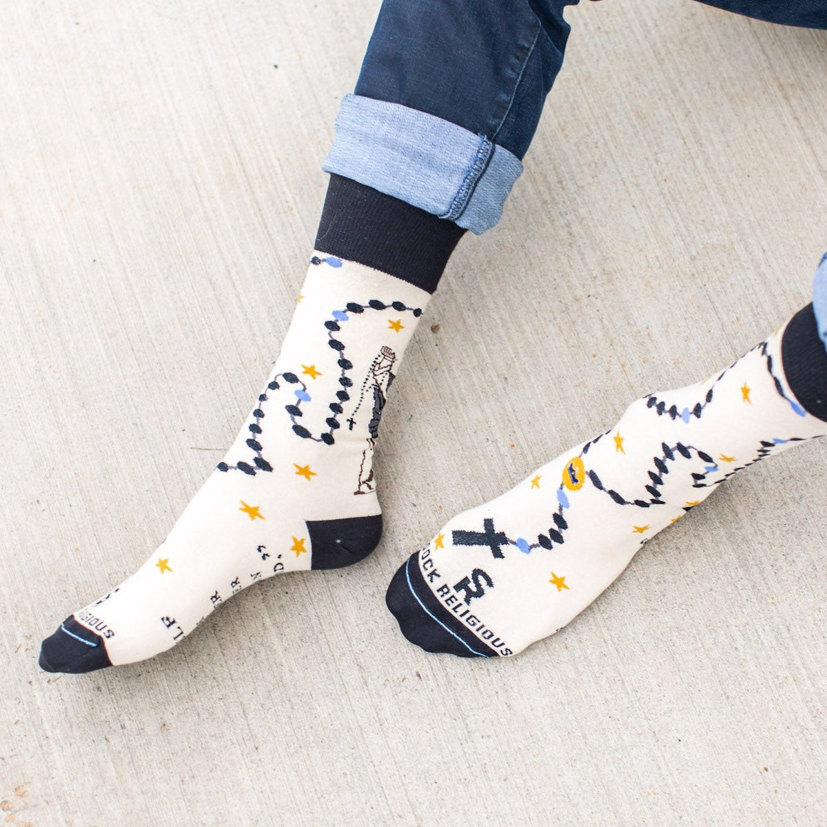 a person sitting on the ground with their feet up wearing a pair of socks with a picture St. Dominic on it