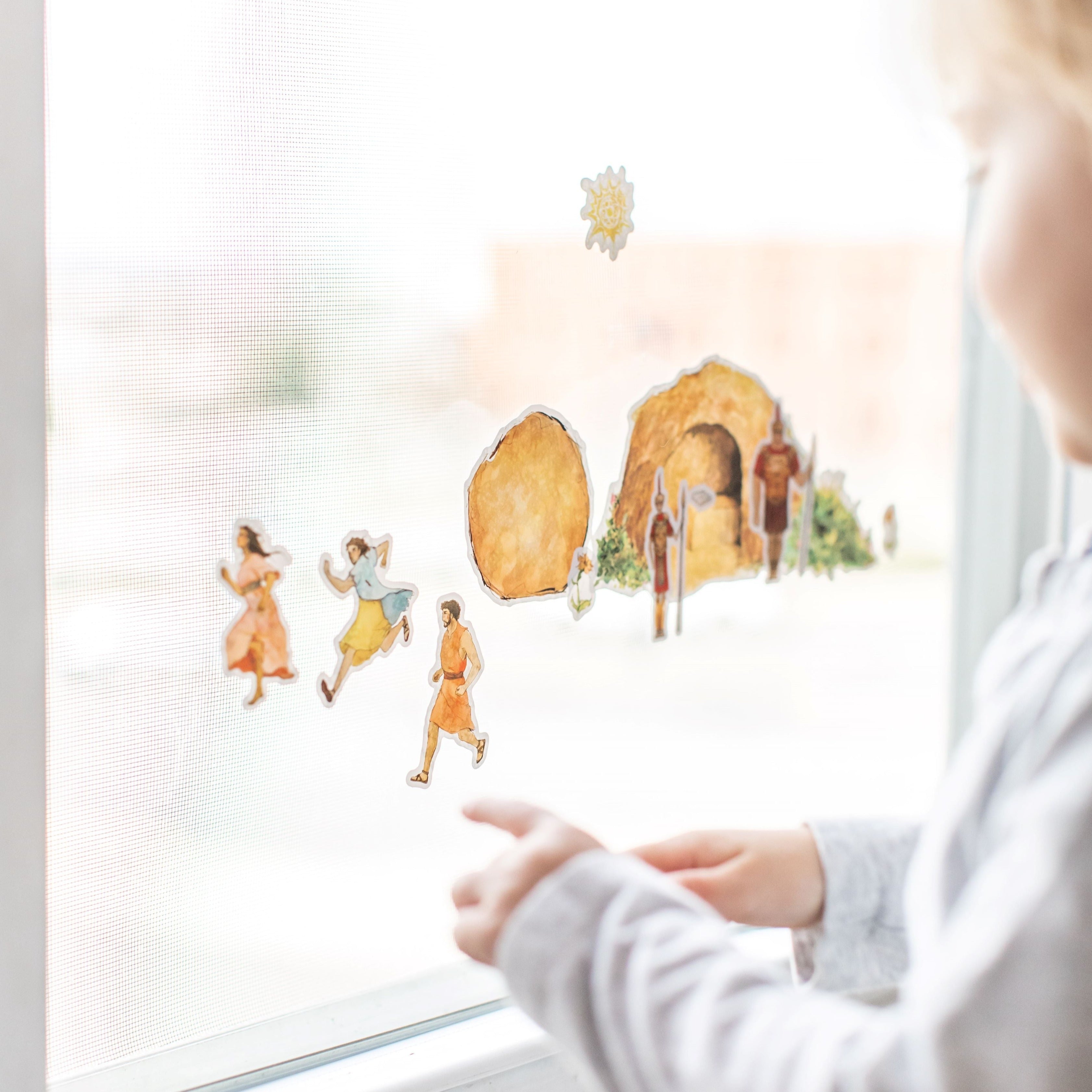 close up of little boy playing with empty tomb cling set on a window
