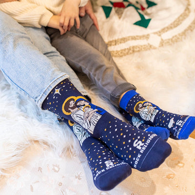 a couple of people sitting on top of a bed wearing a pair of socks with a picture of a man, woman and a baby