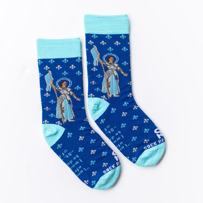 Blue dress socks with St. Joan of Arc on them with a fleur de lis pattern on them the bottom says "I am not afraid, I was born to do this"