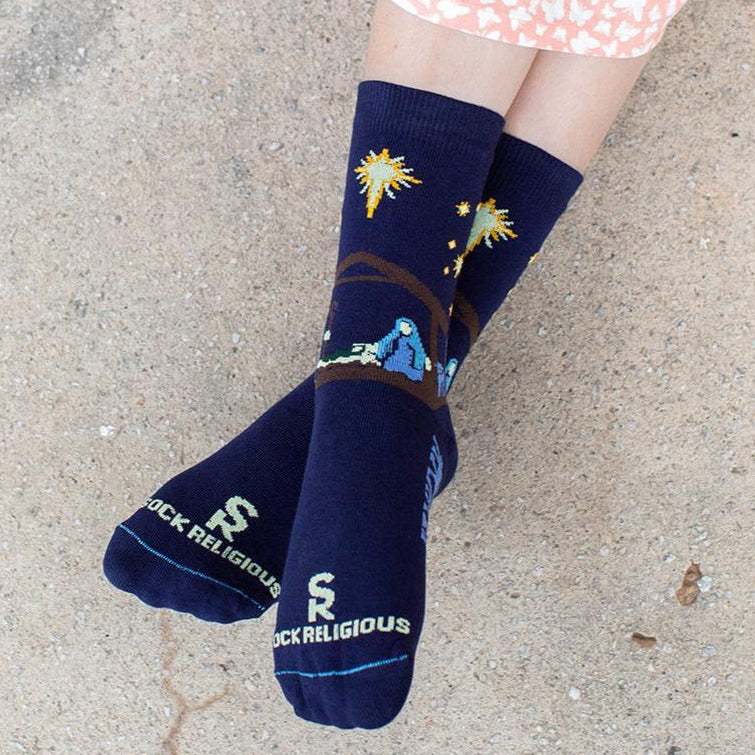 gilr wearing dark navy blue socks featuring simple silhouettes of the manger scene