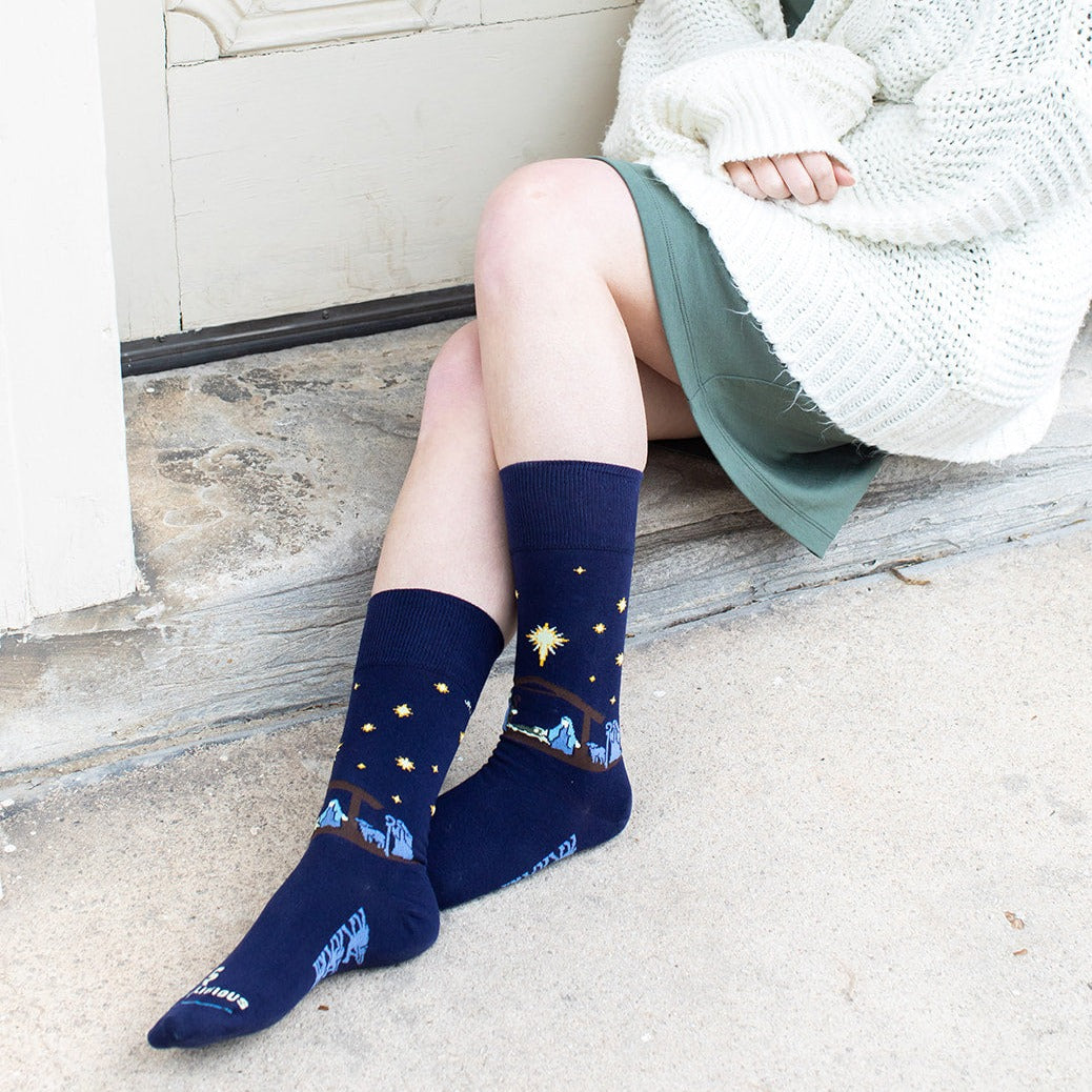 a woman sitting on a step with her legs crossed with the nativity socks on