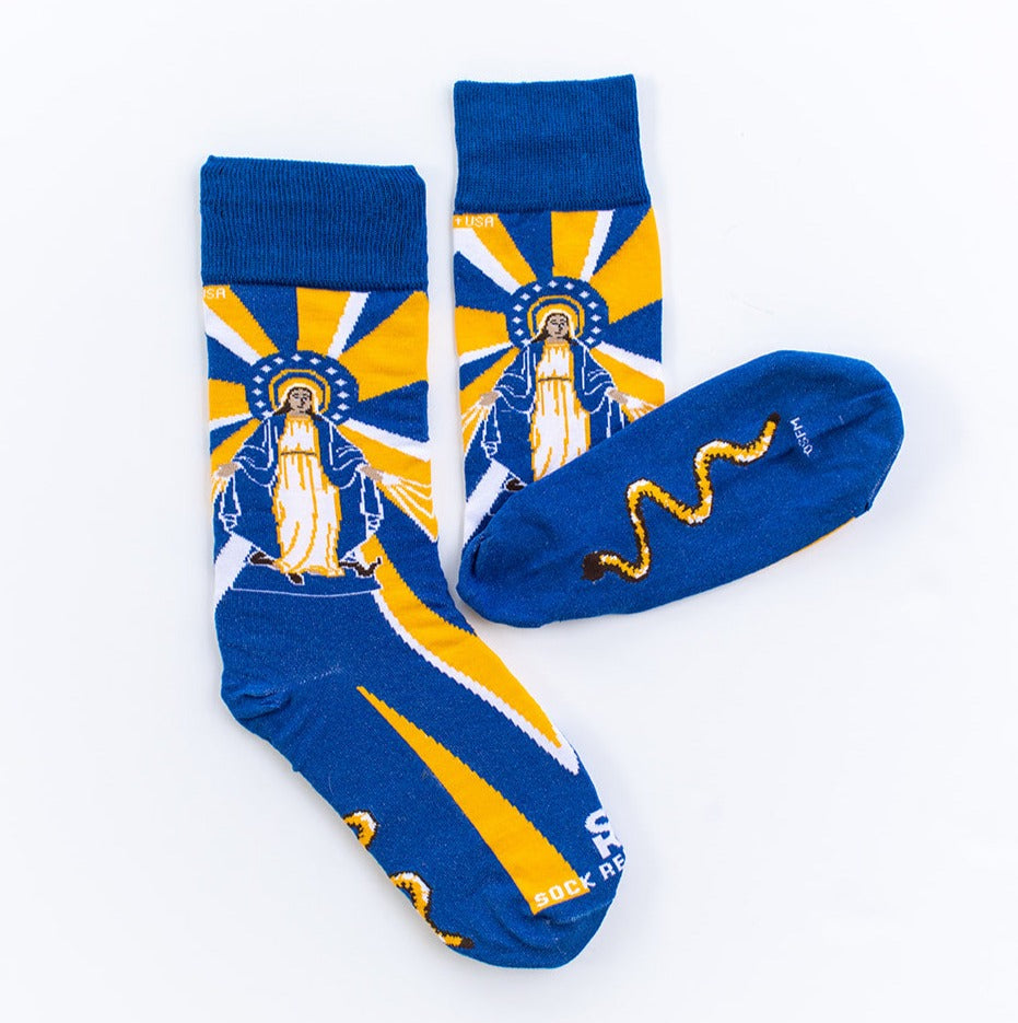 flatlay of Our Lady of Grace socks with Mary, yellow and blue rays and a serpant on the bottom of the foot