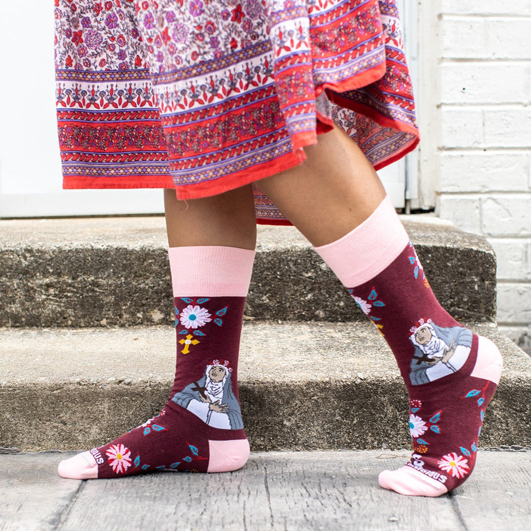 A person standing on steps wearing a pair of pink and red sock with a picture of St. Rose of Lima on it