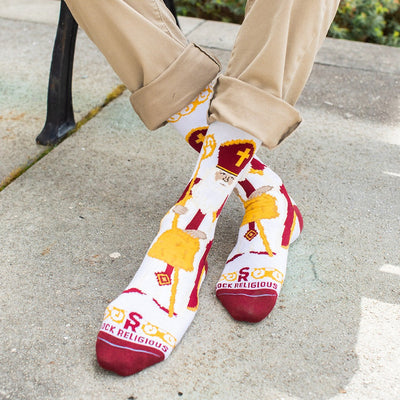 a person sitting on a bench wearing a pair of socks with an picture of St. Nicholas
