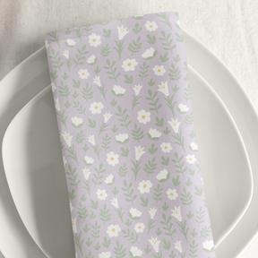Light lilac Easter Alleluia napkin with white floral design placed on a plate in a styled table setting.