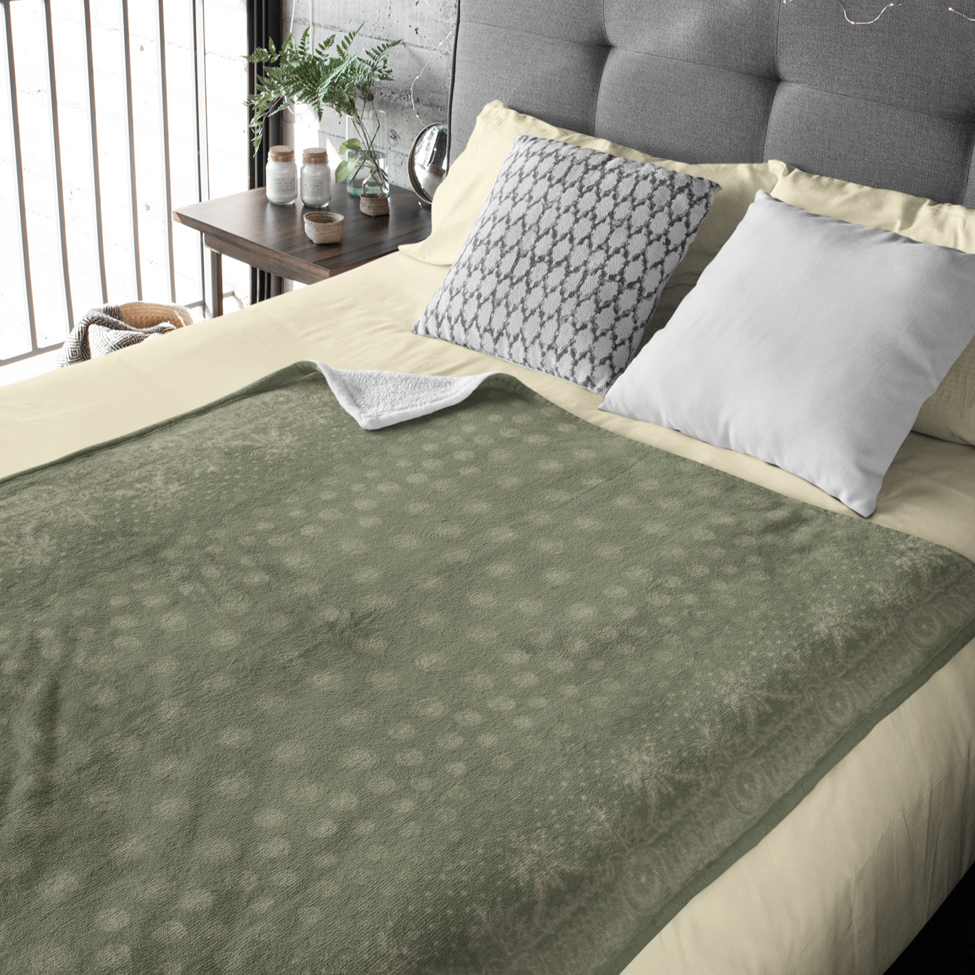 A green and white blanket with a white border, showcasing a gold design of craft symbols by Louis and Zélie. Laying on a bed made for two.