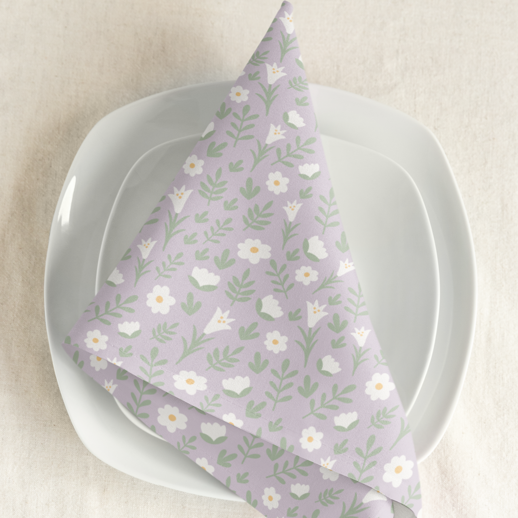 Light lilac Easter Alleluia napkin with white floral design placed on a plate in a styled table setting.

