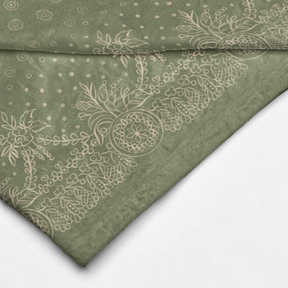 A green and white blanket with a white border, showcasing a gold design of craft symbols by Louis and Zélie.