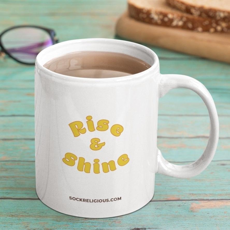 back of mug says 'Rise & Shine' in yellow and orange