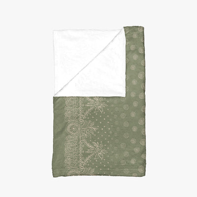 A green and white blanket with a white border, showcasing a gold design of craft symbols by Louis and Zélie.