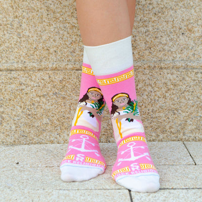 A person standing wearing a pair of pink and white socks with a picture of St. Philomena on it