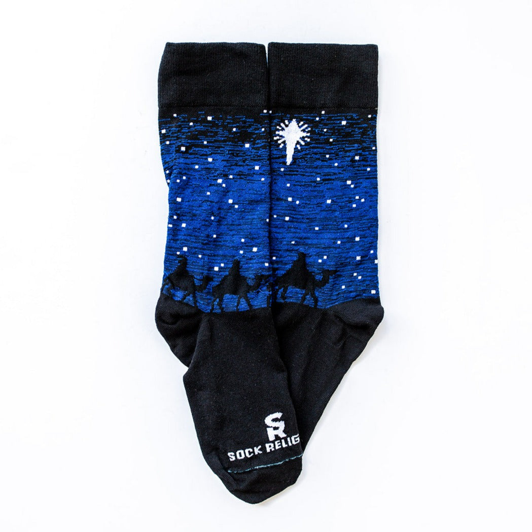 Black and blue socks featuring silhouettes of the 3 wisemen on camels following a bright white star of bethlehem