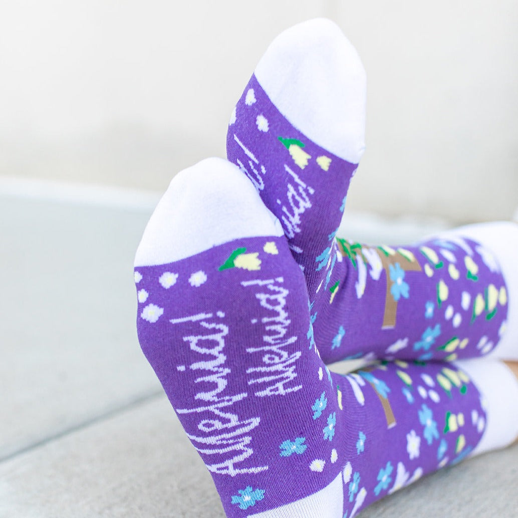 a person wearing a pair of purple socks with a cross and flowers on it