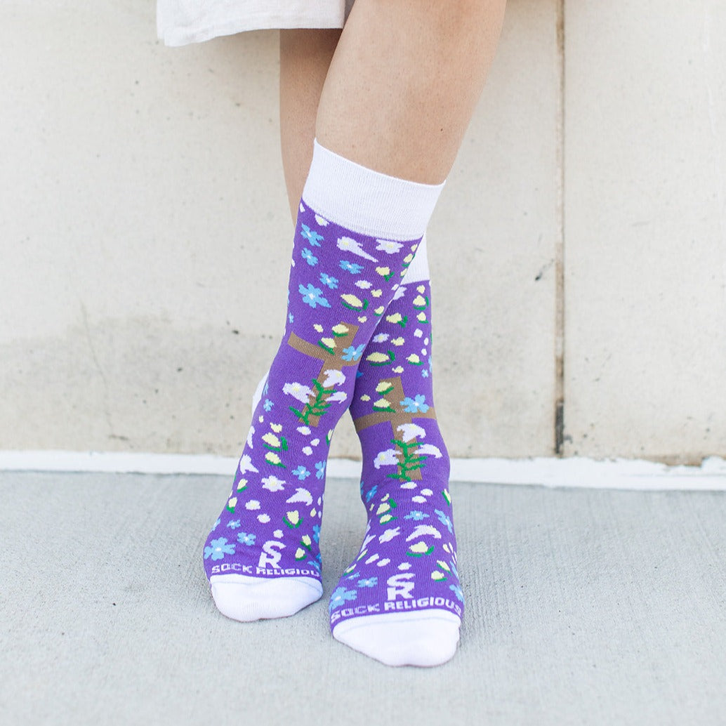 a woman wearing a pair of purple socks with a cross and flowers on it