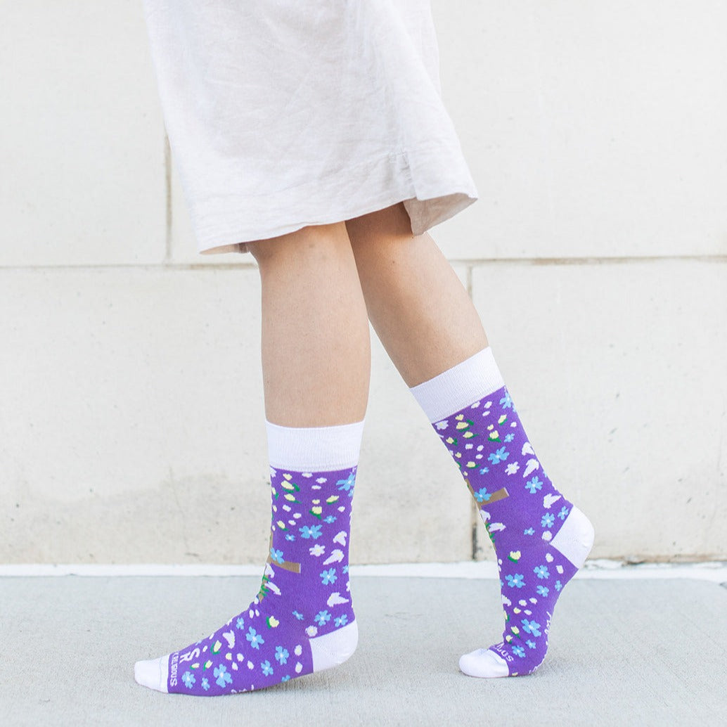 a woman wearing a pair of purple socks with a cross and flowers on it