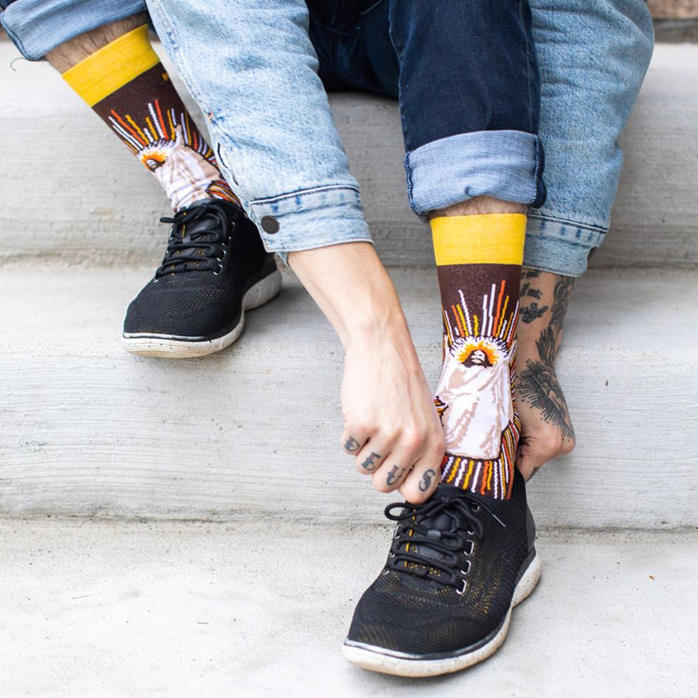 a person sitting on a step wearing a pair of brown socks with a picture Jesus Christ