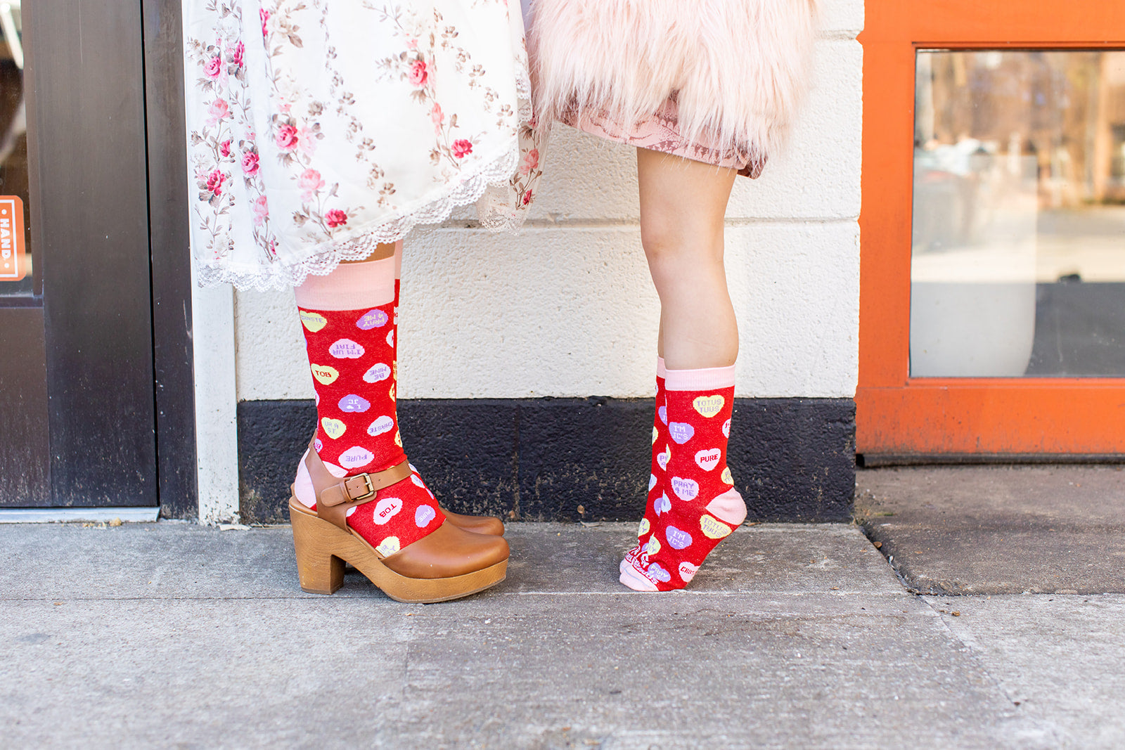 two person wearing a pair of red socks with hearts on them